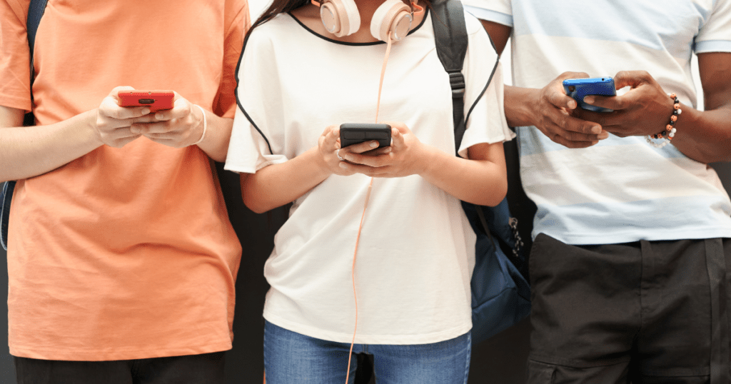 Three young people seen up close using their cell phones